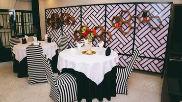 A dining area with round tables, black and white striped chairs, and a decorative wall with hexagonal patterns.