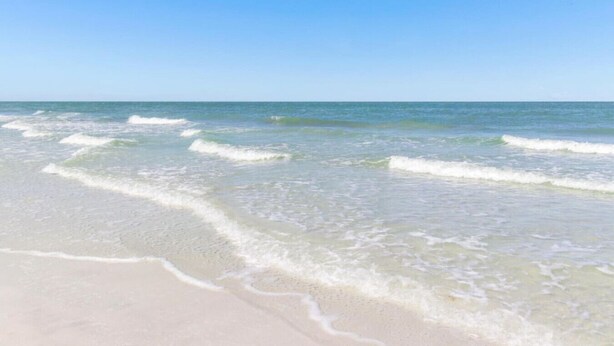 Una playa con agua cristalina y olas suaves.