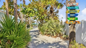 Un sendero bordeado de palmeras y plantas tropicales que conduce a una playa.