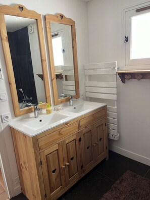 A bathroom with two sinks, wooden cabinets, a towel rack, and a mirror.