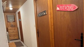Un pasillo con un banco de madera, una puerta con la leyenda "PISTE NOIRE" y un cartel que indica "PISTE ROUGE".