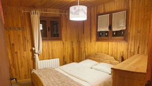 Una habitación de madera con una cama, un armario de madera y una ventana con cortinas.