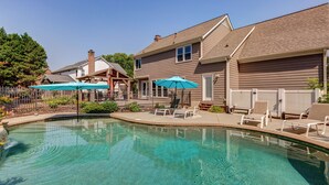 A swimming pool with lounge chairs and umbrellas, surrounded by a fenced patio area. - Spacious Oasis with heated pool/spa, covered patio, office & near Lake Norman (Mooresville)