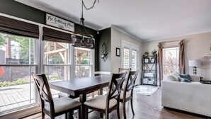 A dining area with a wooden table and chairs, a chandelier, and large windows overlooking a deck. - Spacious Oasis with heated pool/spa, covered patio, office & near Lake Norman (Mooresville)