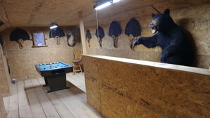 Quarto com piso de madeira, uma mesa de pebolim, uma cadeira e uma estátua de urso.