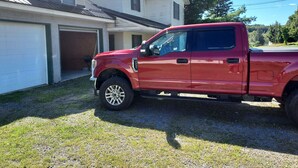 Uma caminhonete vermelha estacionada em frente a uma casa com garagem.