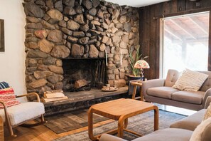 A cozy living room with a stone fireplace, a sofa, a rocking chair, and a coffee table.