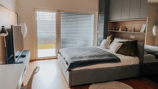 Een moderne slaapkamer met een groot bed, een bureau en een kledingkast.