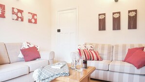 Un salon avec deux canapés, une table basse et des œuvres d’art murales.