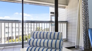 Un balcon avec un canapé à rayures, un rideau à motifs et une vue sur des immeubles et de la verdure.