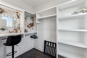 A walk-in closet with a vanity mirror, shelves, and a chair. - Hot Tub in Downtown! Stunning Design & Features (Nashville)