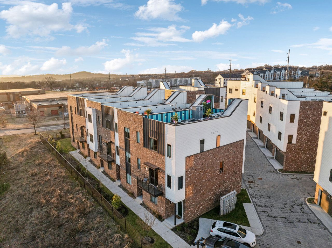 Un moderno edificio residencial de varios pisos con techo plano, ventanas amplias y un patio central.