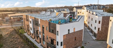 Un moderno edificio residencial de varios pisos con techo plano, ventanas amplias y un patio central.