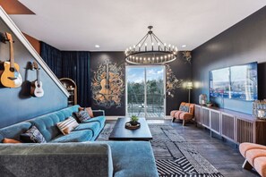 A modern living room with a blue sofa, a coffee table, and a large window with a view.