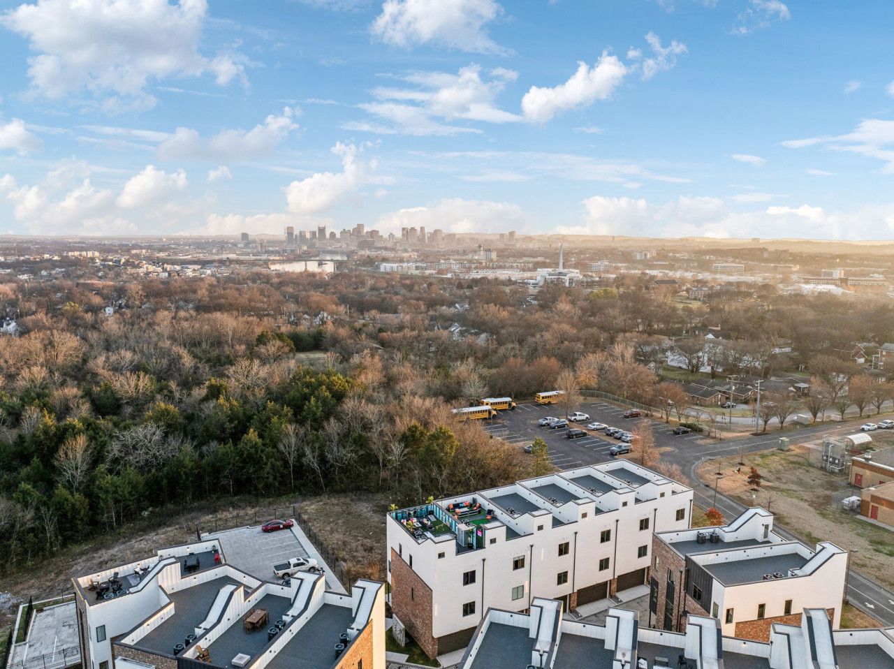 A multi-story building with a flat roof, surrounded by a parking lot and a dense forest.