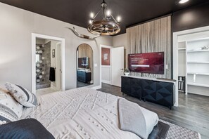 A modern bedroom with a large bed, a TV, and a wardrobe.