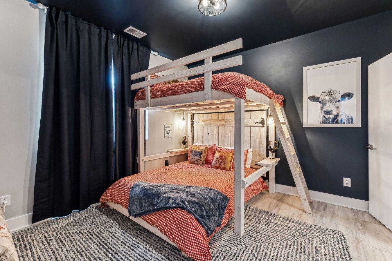 Una cama litera con escalera de madera, colcha de cuadros rojos y blancos, y una alfombra con estampado en blanco y negro.