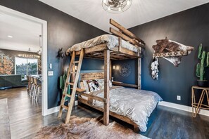 Een stapelbed met een ladder, een rustieke inrichting en uitzicht op de eetruimte.