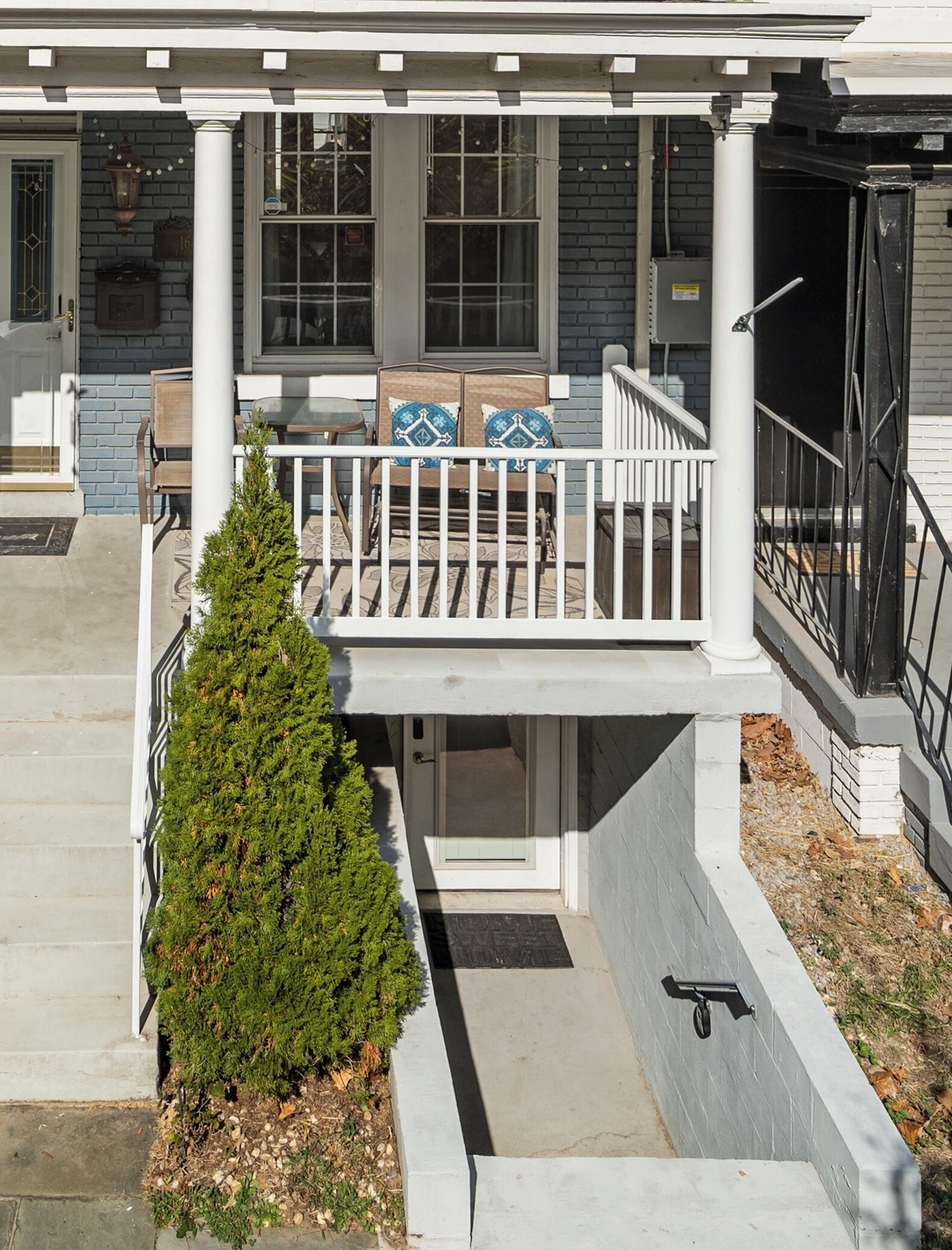 A two-story building with a covered porch, a small tree, and a mailbox.