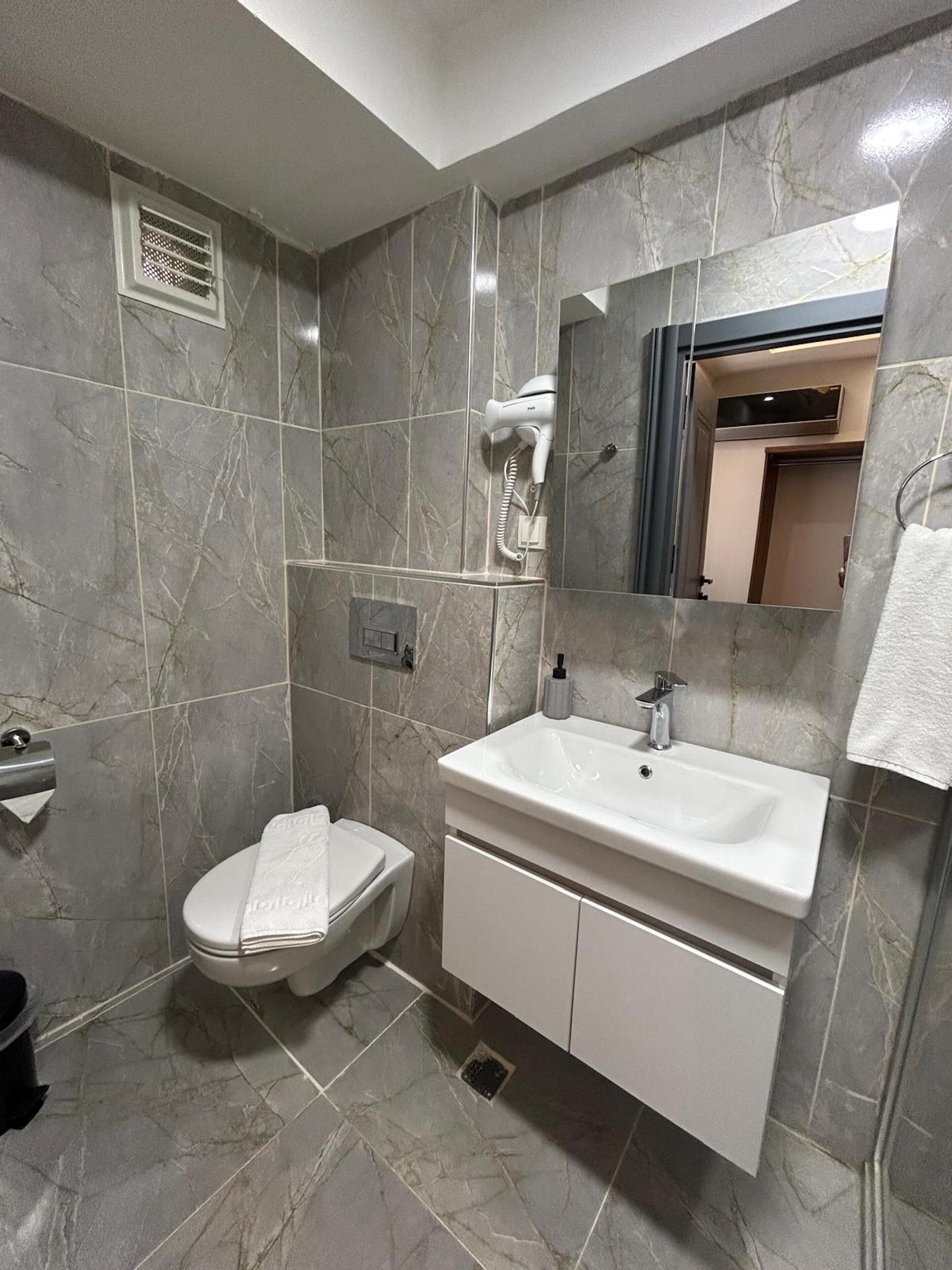 Une salle de bain avec des toilettes, un lavabo et un miroir.