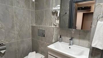 Une salle de bain avec des toilettes, un lavabo et un miroir.