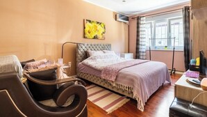 A bedroom with a bed, a massage chair, a small desk, and a window with curtains. - Chic apartment -Dorcol city center with parking (Beograd)