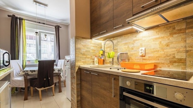 A modern kitchen with a stone backsplash, wooden cabinets, and a built-in oven. - Chic apartment -Dorcol city center with parking (Beograd)