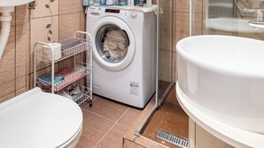 A compact bathroom with a washing machine, toilet, and shower area. - Chic apartment -Dorcol city center with parking (Beograd)
