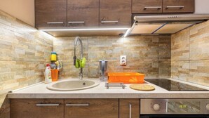 A modern kitchen with a stone backsplash, wooden cabinets, a stainless steel sink, and an oven. - Chic apartment -Dorcol city center with parking (Beograd)