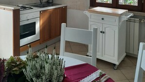 A kitchen with wooden cabinets, a stove, and a window with curtains. - La Civetta, elegant one-bedroom apartment with garden, private parking 10min from the city (NAVE)