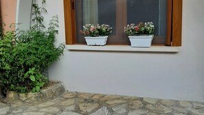 A stone-paved entrance with a window featuring two potted plants. - La Civetta, elegant one-bedroom apartment with garden, private parking 10min from the city (NAVE)