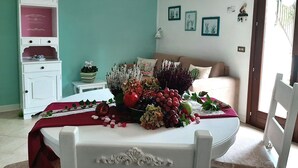 A dining table with a red tablecloth, surrounded by various fruits and a white chair. - La Civetta, elegant one-bedroom apartment with garden, private parking 10min from the city (NAVE)