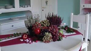 A dining table with a fruit centerpiece, white cabinets, and a teal wall. - La Civetta, elegant one-bedroom apartment with garden, private parking 10min from the city (NAVE)