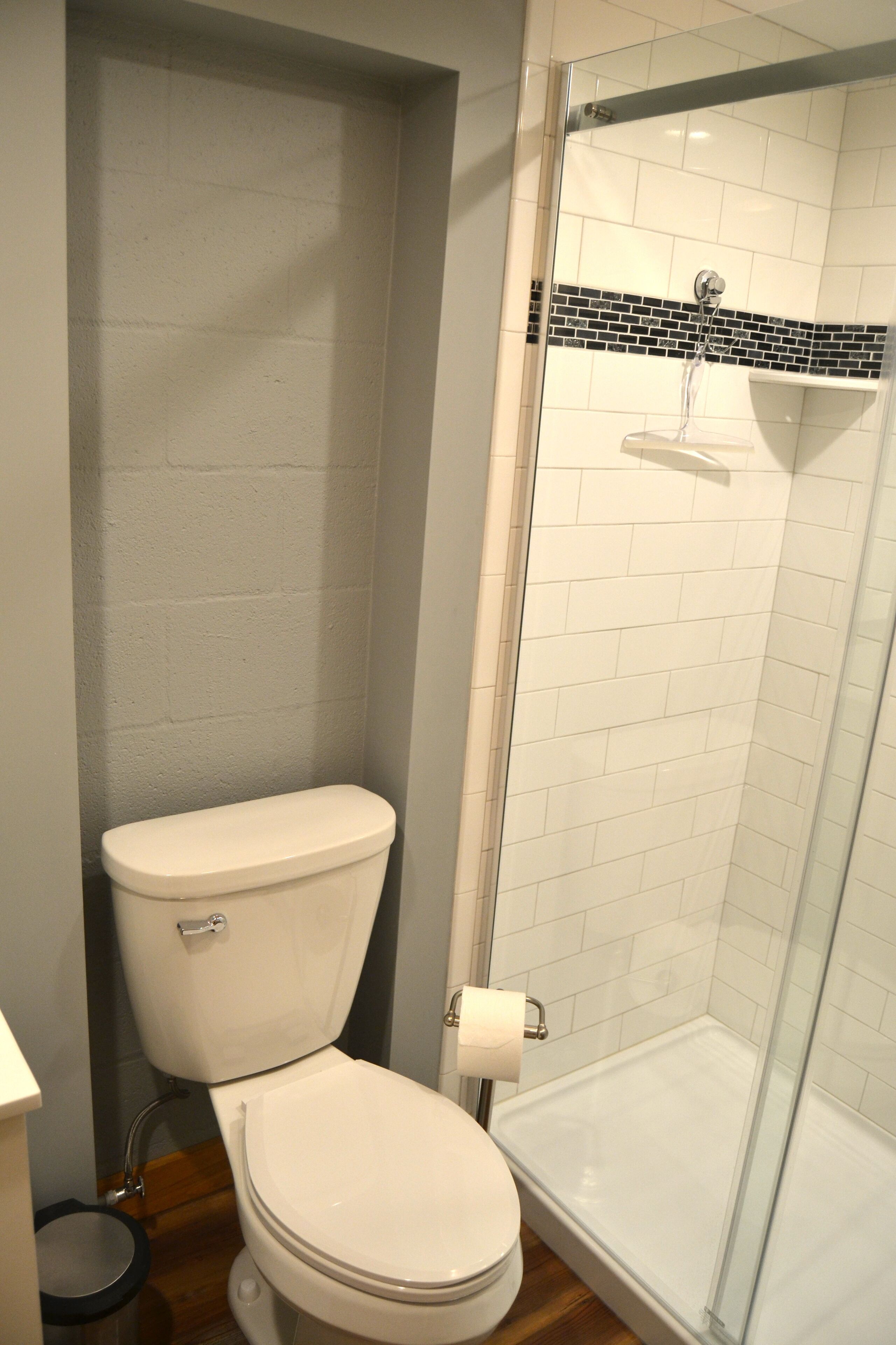 A bathroom with a toilet, a glass shower enclosure, and a tiled wall.