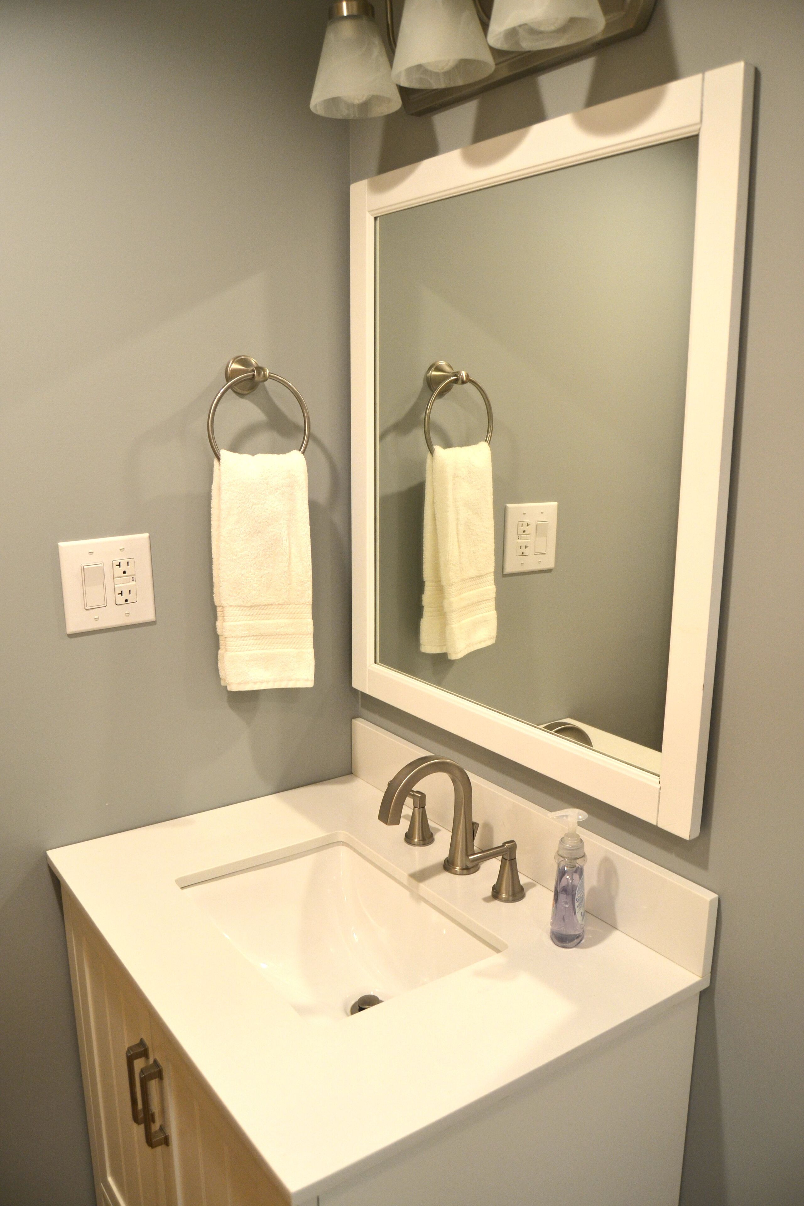 A bathroom with a white sink, a mirror, and two towels hanging on towel rings.