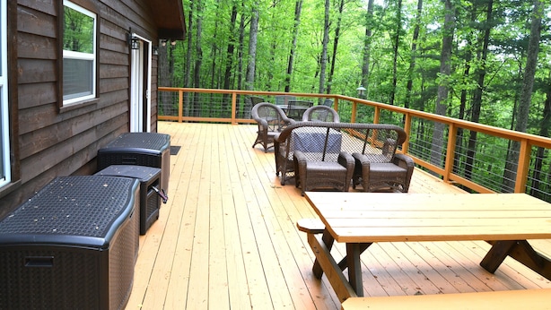 A wooden deck with outdoor furniture, including a table and chairs, overlooking a forested area. - Locust Flats - PET-FRIENDLY MOUNTAIN Cabin = Decks-Views-Firepit (Franklin)