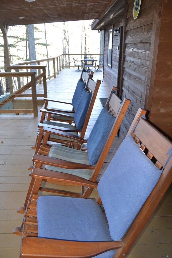 A row of wooden lounge chairs with blue cushions on a wooden deck.