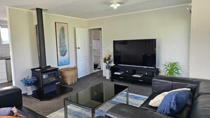 Ein modernes Wohnzimmer mit einem schwarzen Sofa, einem Glastisch, einer schwarzen Unterhaltungseinheit, einem Kamin und einem großen Fernseher.