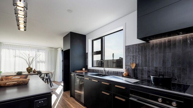 Una cocina moderna con armarios negros, un amplio ventanal y una mesa de comedor de madera.