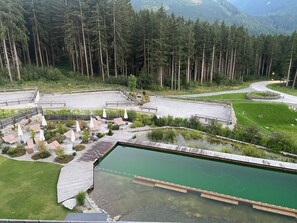 A landscaped area with a pool, seating areas, and a view of a forested mountain range.