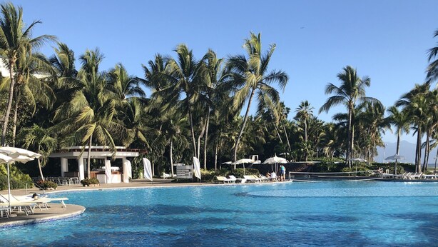 A clear blue pool surrounded by palm trees and lounge chairs. - 3-Bedroom Vidanta Grand Luxxe (Nuevo Nayarit)