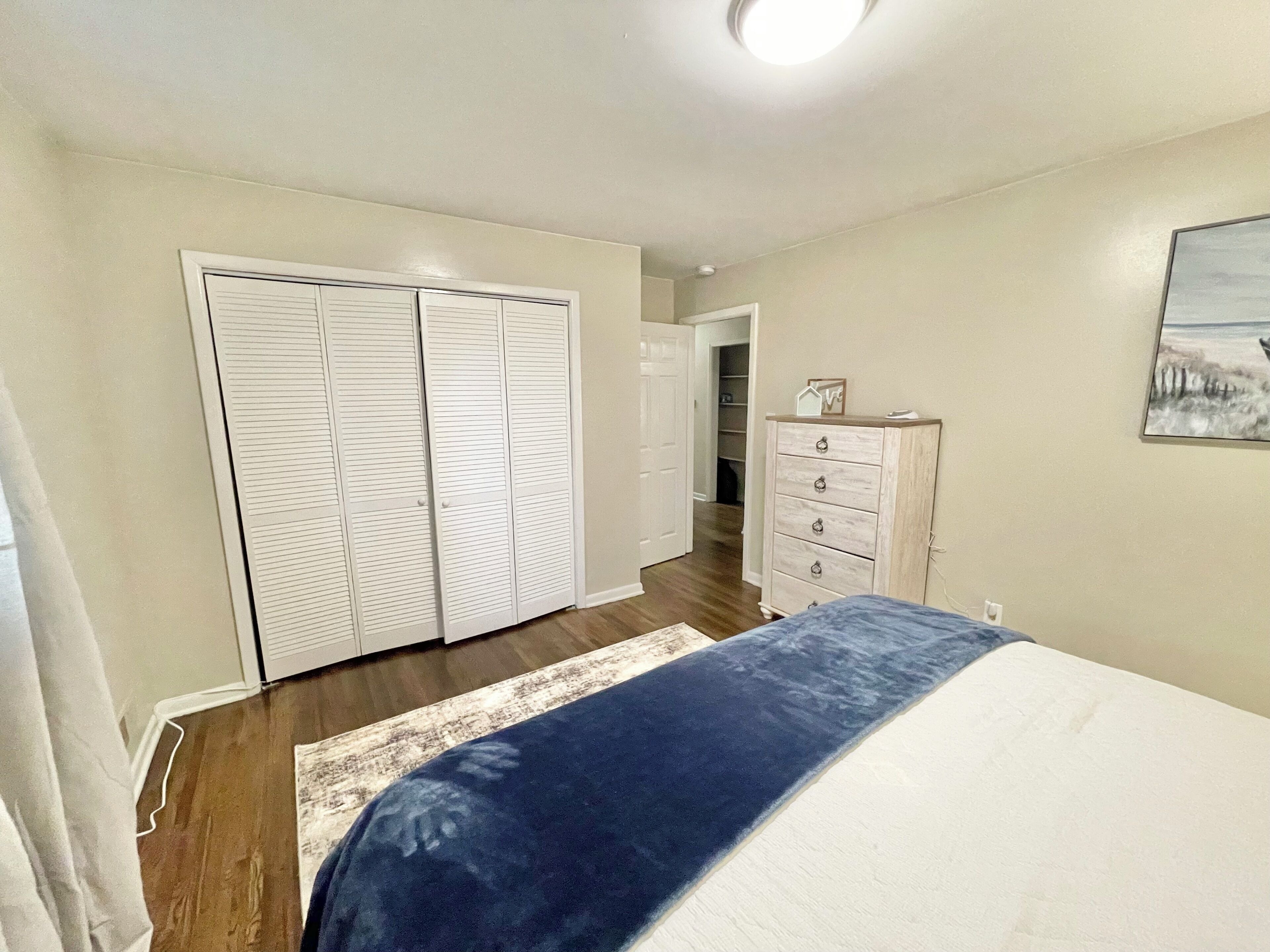 Un dormitorio con cama, cómoda y armario.