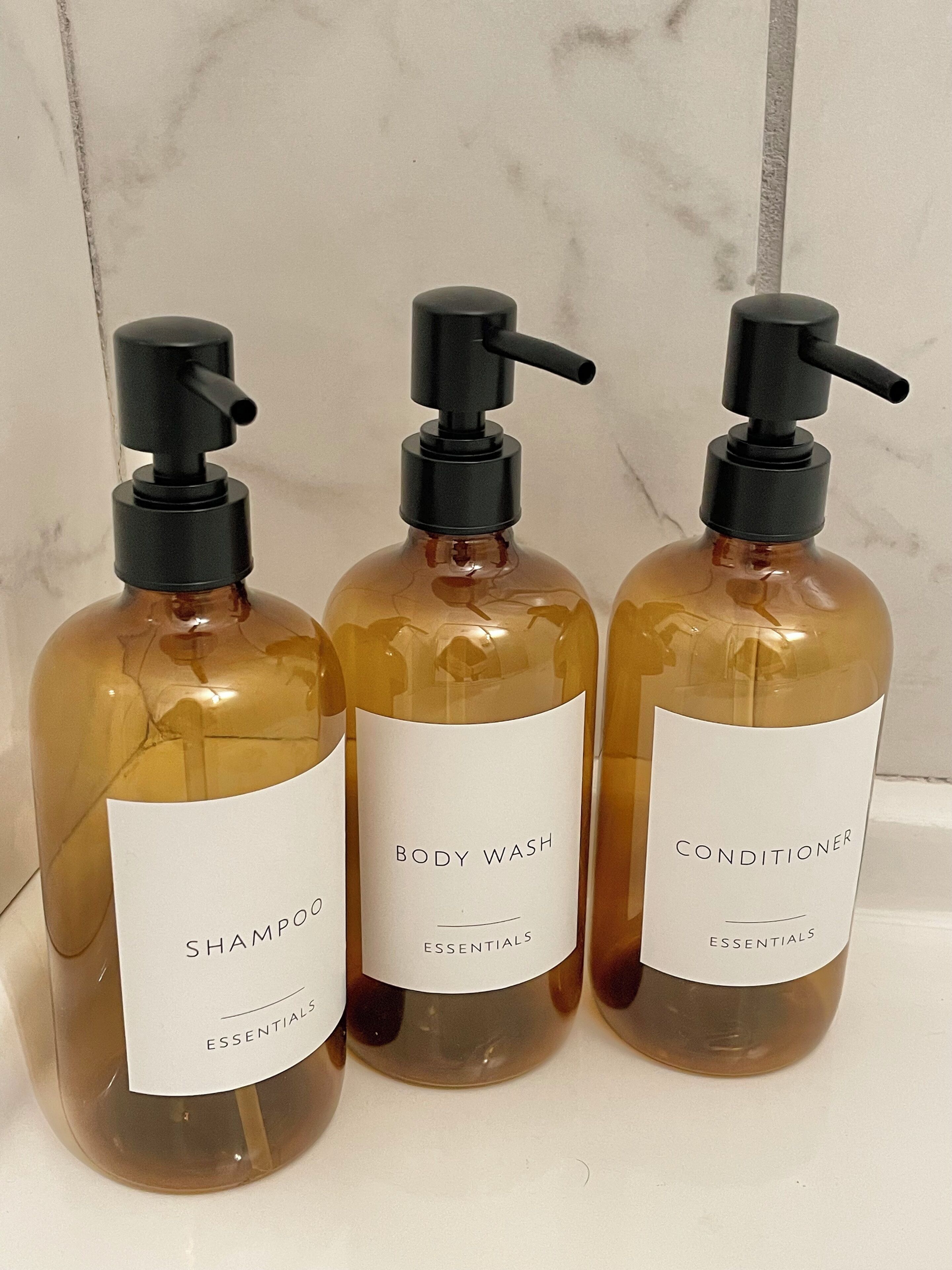 Trois bouteilles de gel douche et d’après-shampoing sur une surface blanche.