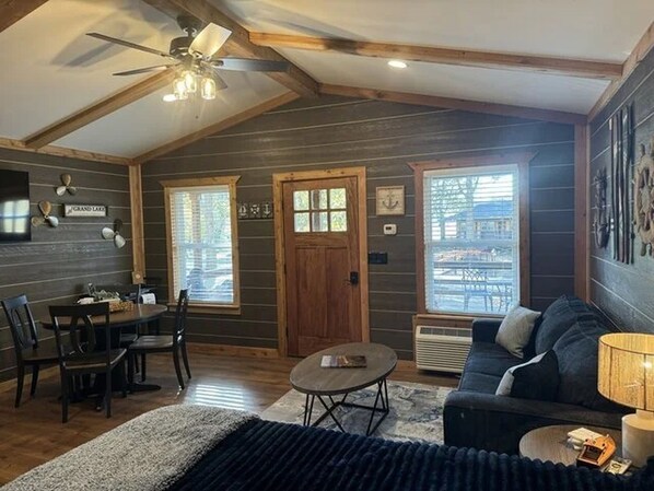 A cozy room with a dining table, chairs, a sofa, a ceiling fan, and a large window.