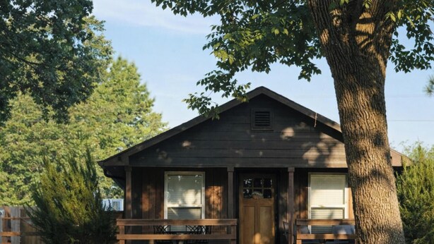 Une cabane en bois avec une véranda, une porte et des fenêtres.
