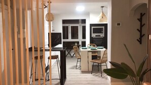 A modern kitchen with a black countertop, white cabinets, and a dining area with wicker chairs and a white table. - Apartment in the Arena area of Gijon, near the beach of San Lorenzo.  (Gijón)