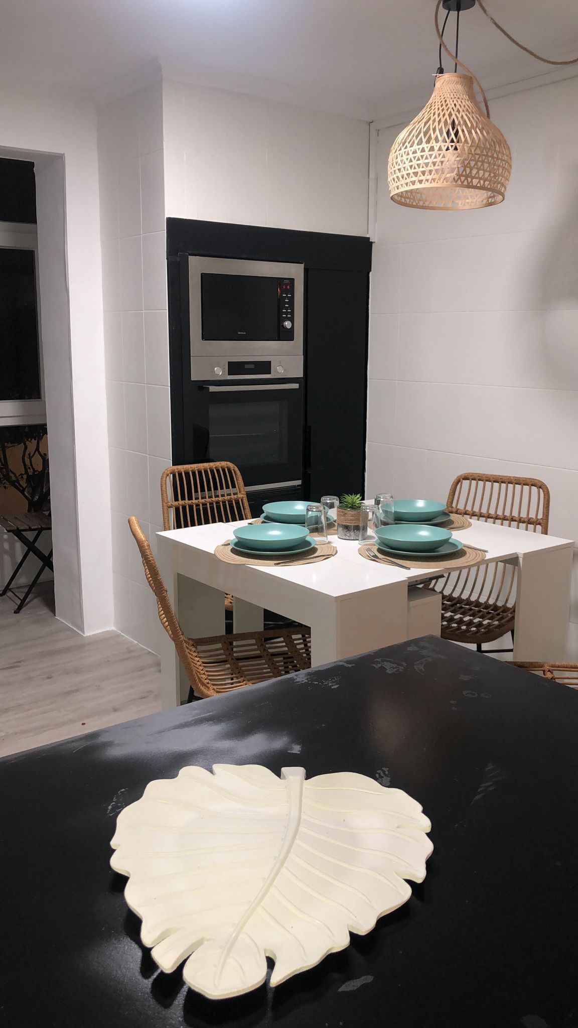 A dining area with a black table, white walls, and a black and white tiled backsplash.
