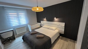 A modern bedroom with a bed, bedside tables, a desk, and a crib. - Apartment in the Arena area of Gijon, near the beach of San Lorenzo.  (Gijón)
