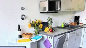 A small kitchenette with a microwave, sink, and a dining area with two chairs and a table. - stayMA Apartment HeiterKite relax surf fishing, 10m from the Baltic Sea (Wiek)
