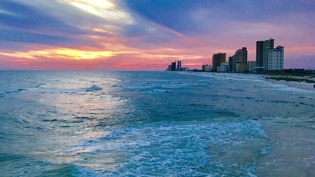 A beach with waves and a sunset.